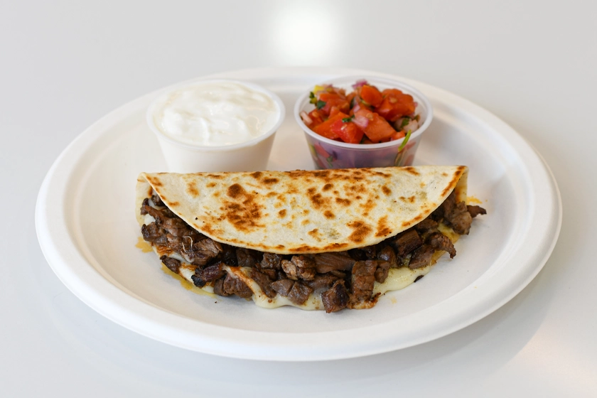 juicy, cheesy carne asada tacos with side sour cream and salsa with tomatoes from tacos del barrio brooklyn