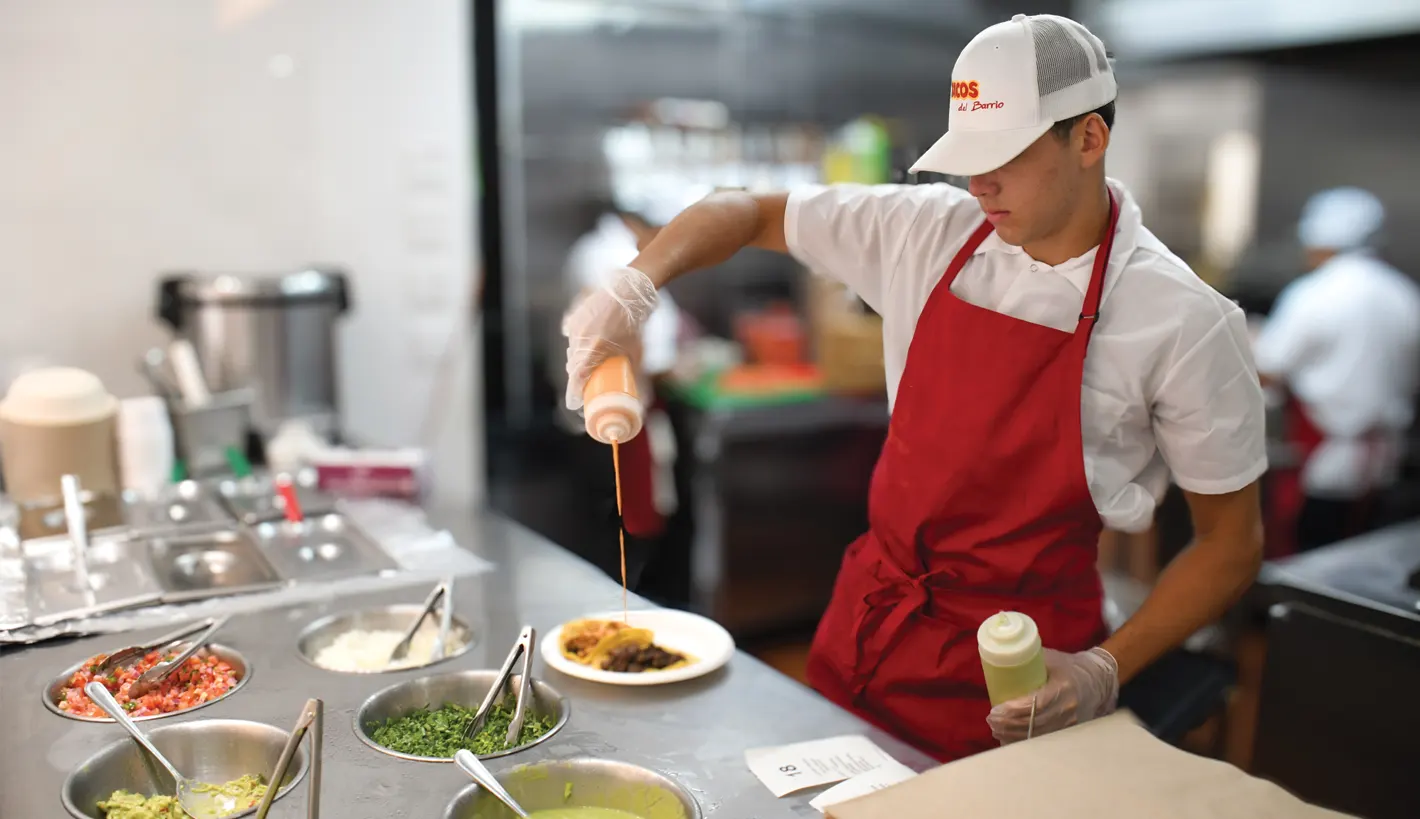 a man putting sauce on a taco meal
